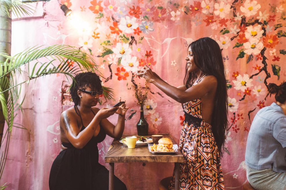 cheerful black women taking pictures on food on sm
