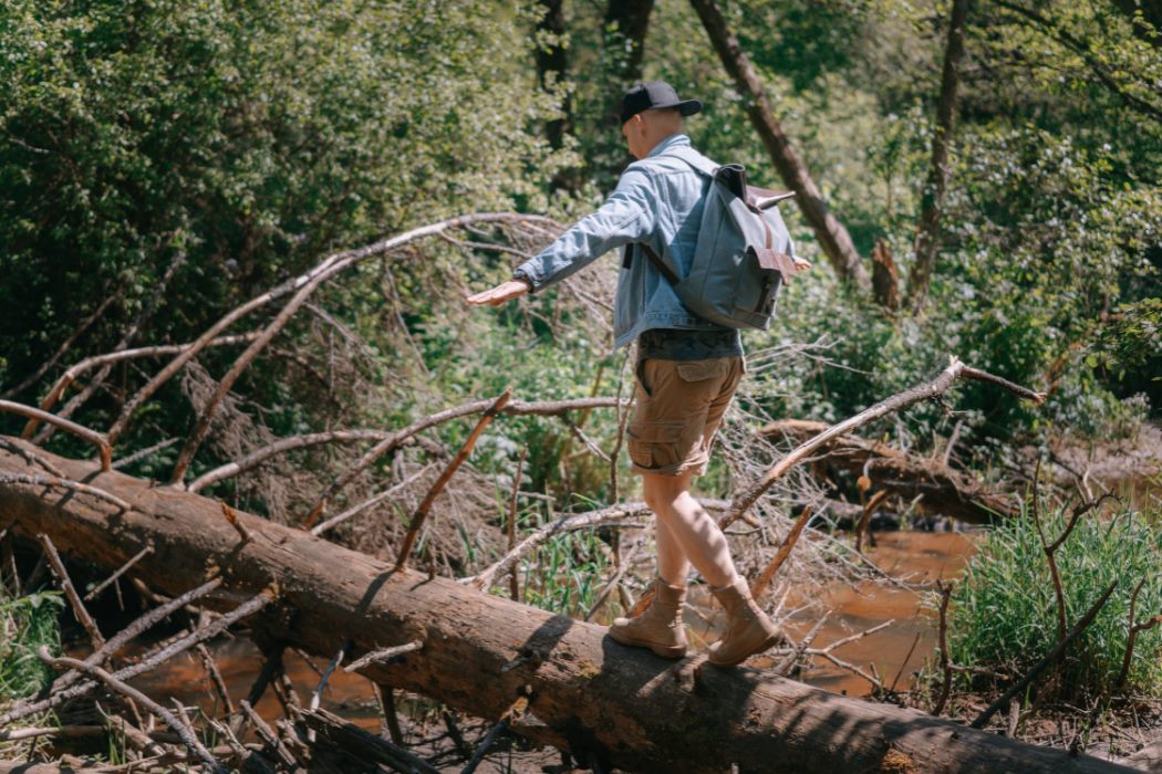 man in denim jacket walking on a log · free stock