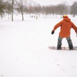 person in orange jacket snowboarding · free stock